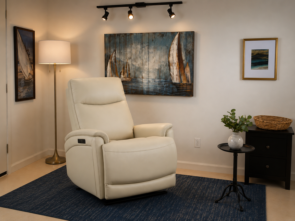 A cream-colored leather recliner chair placed on a blue textured area rug in a styled room setting with a floor lamp, wall art, and a small side table.